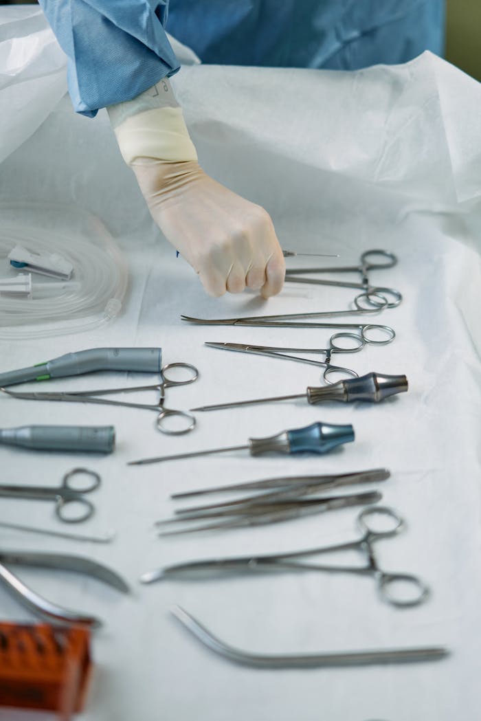 Close-up of surgical tools arranged on a table with gloved hand in an operating room.